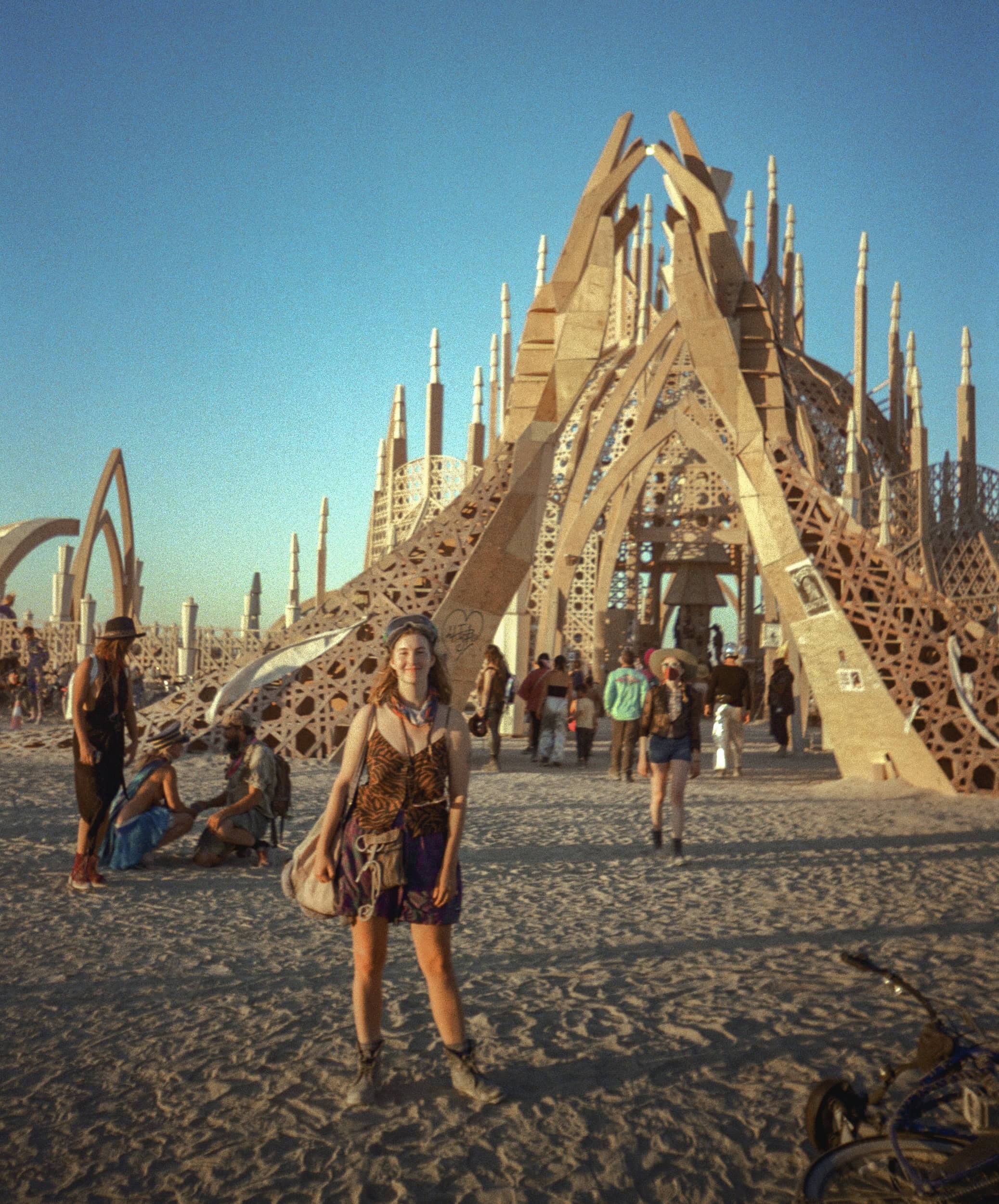 Me at Burning Man standing on the dusty in front of an art installation wooden temple looking at the camera.