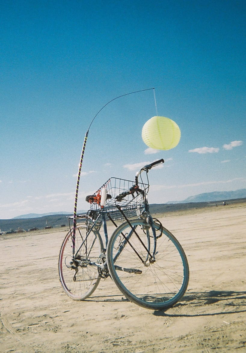 A bicycle at Burning Man decorated with a tall marker with a paper lantern attached to its end.