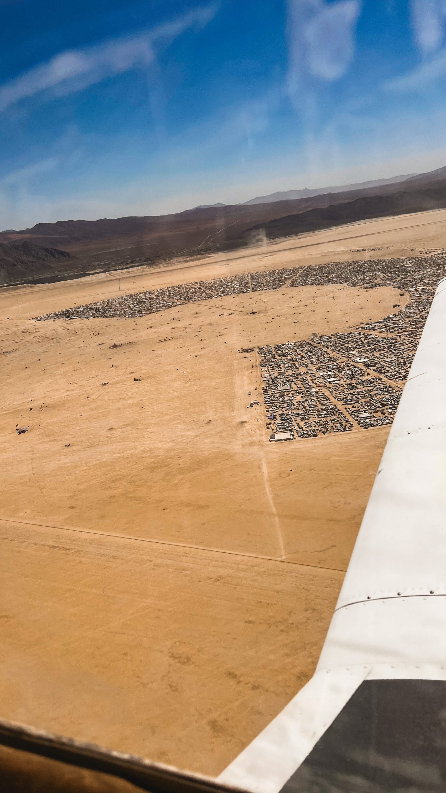 View from a plane ride overlooking Black Rock City city layout and the surrounding hills in the distance.