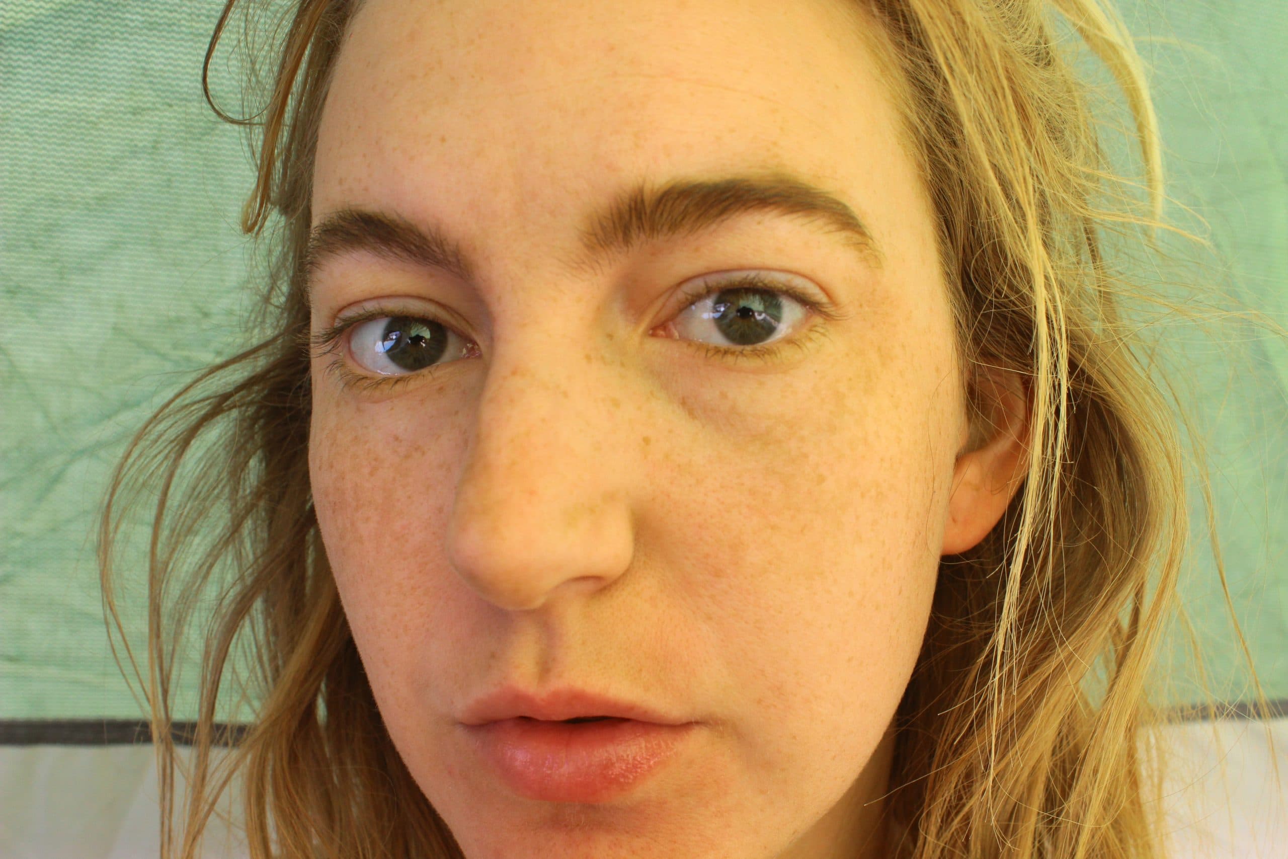 Tasha looking into the camera inside a tent with her eyes a bit puffy and chapped lips and hair dusty and dirty.
