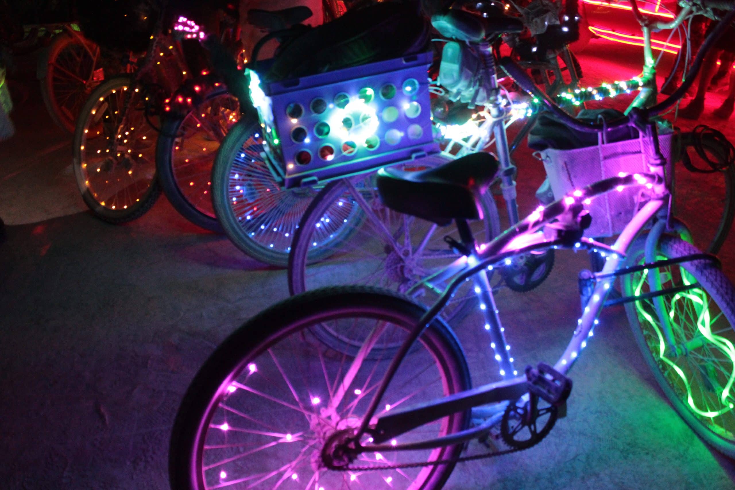 Bicycles at Burning Man at night with many vibrant lights and bike baskets.