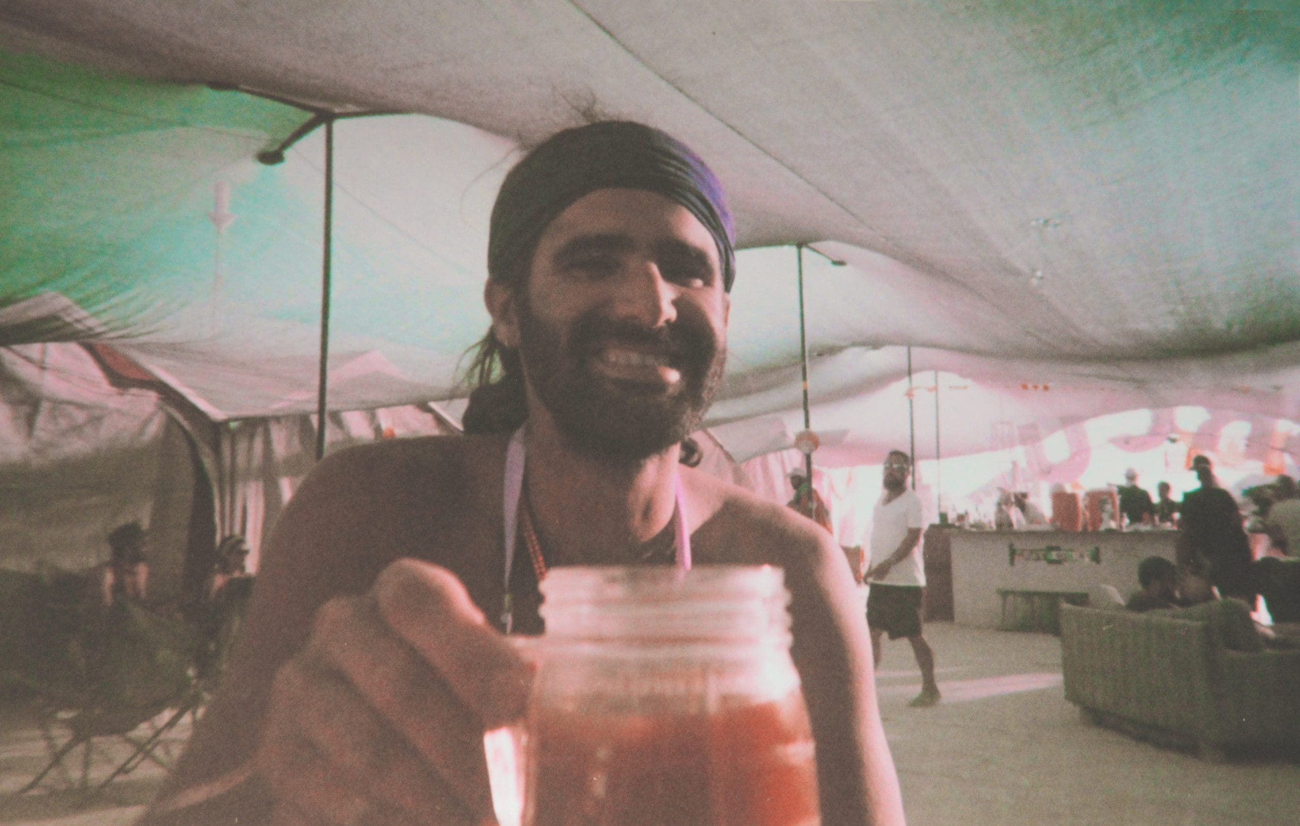 Diego at his first Burning Man smiling with a portable cup full of bloody mary in his hand.