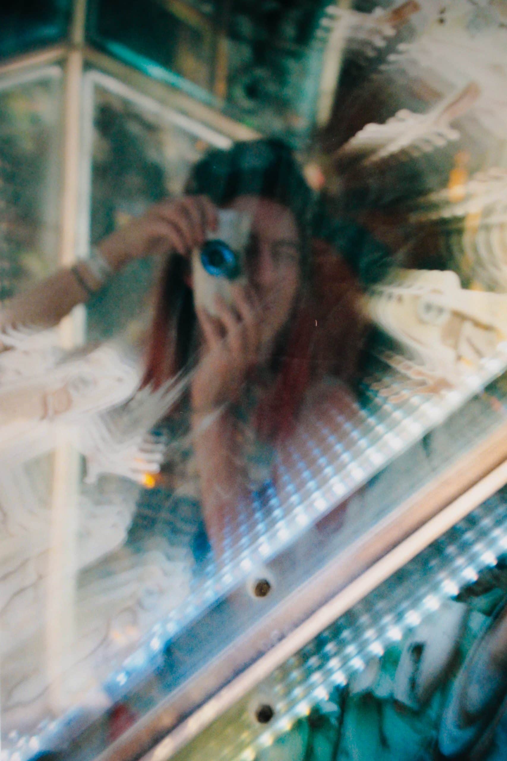 Tasha taking a self with a disposable camera in a reflective surface of an art installation.