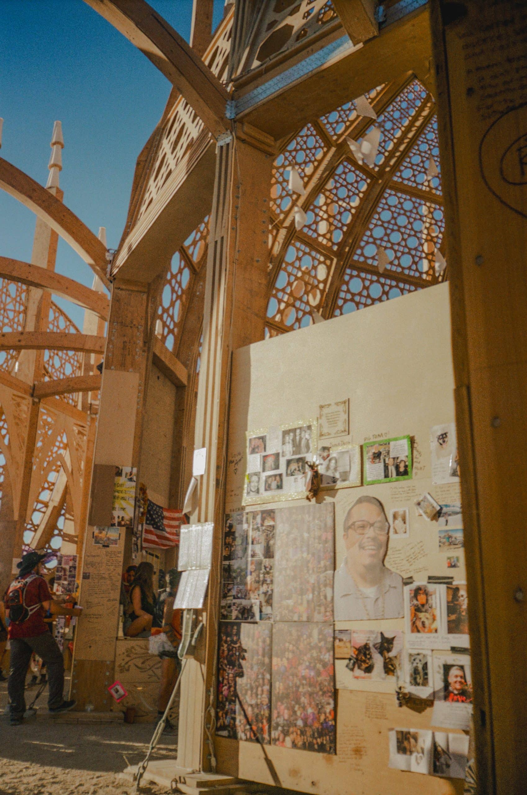Inside the Temple of Together wooden structure at Burning Man. Intricate design with many posters, photos, and written messages on the walls.