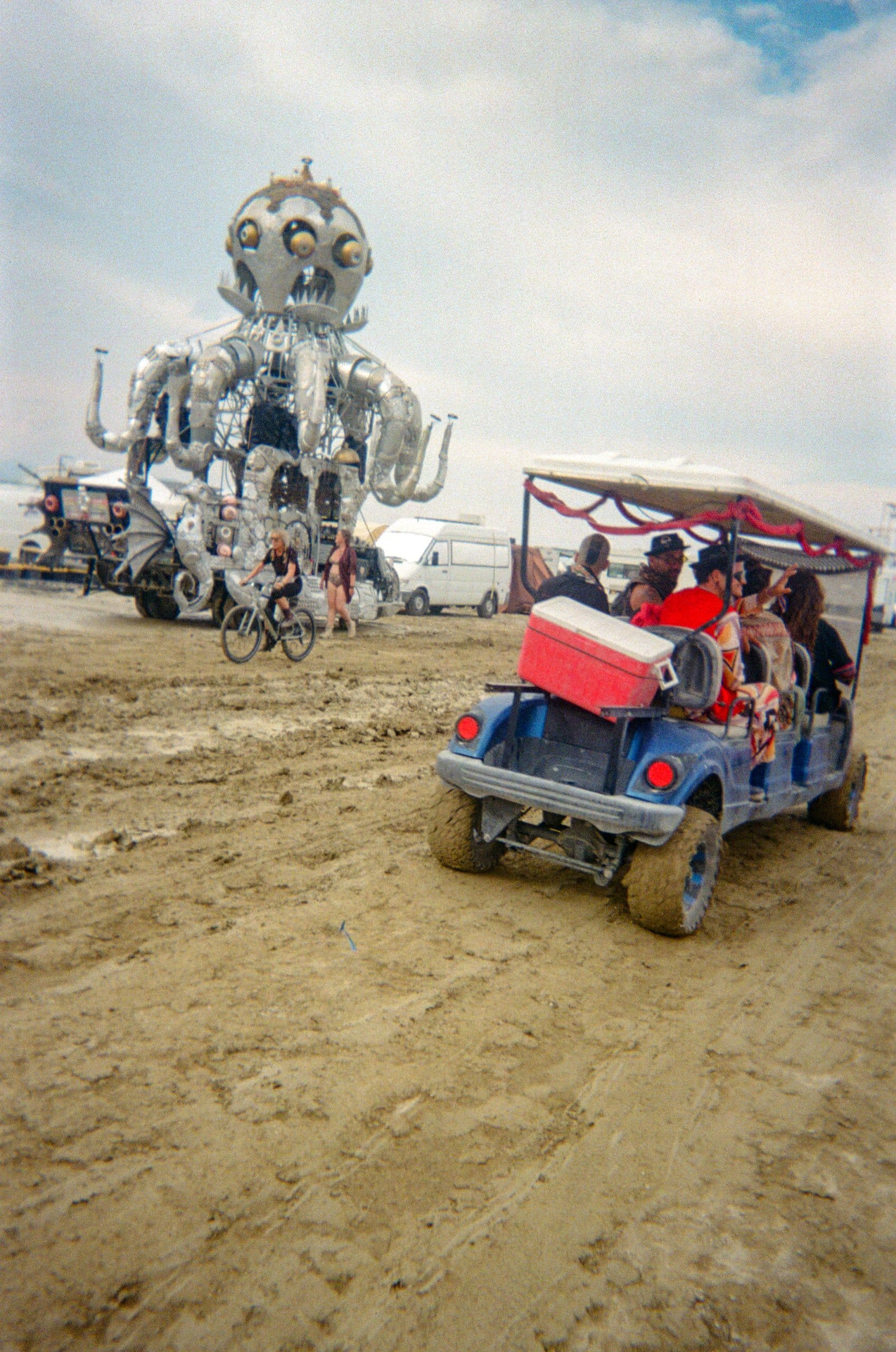 El Pulp Mechanico octopus art car and a golf cart buggy on the wet bumpy roads at Burning Man after it had rained.