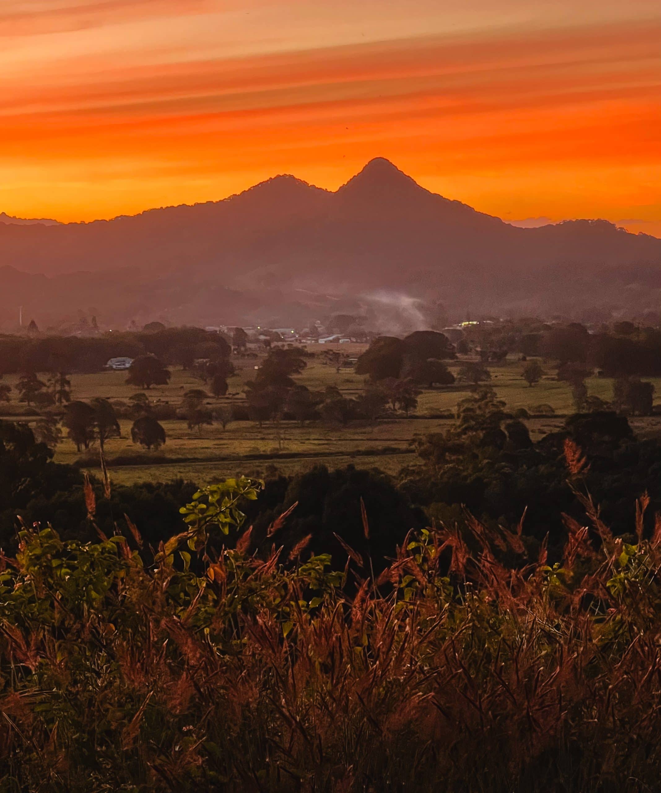 Orange sunset skies surrounding Mount Chincogan in Mullumbimby, Australia.