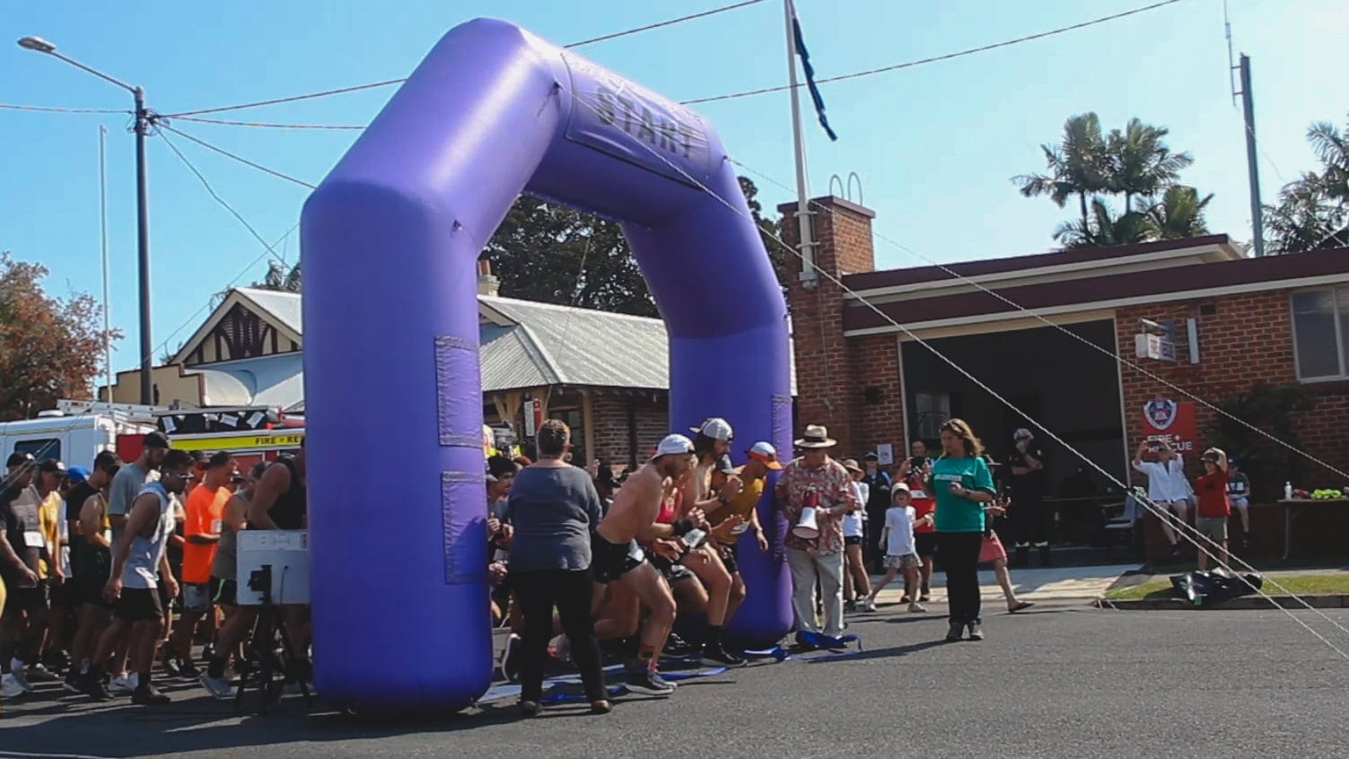 The runners bursting through the starting line under an inflatable purple arch at the Chinny Charge 2024 in Mullumbimby.